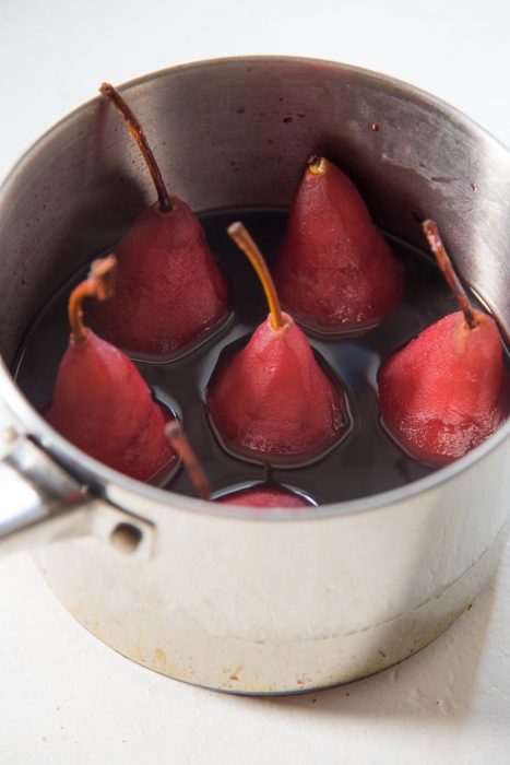 Red Wine poached pears in the red wine liquid, cooling in the saucepan.