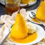 Saffron poached pear served on a small plate with poaching syrup and mascarpone cheese.