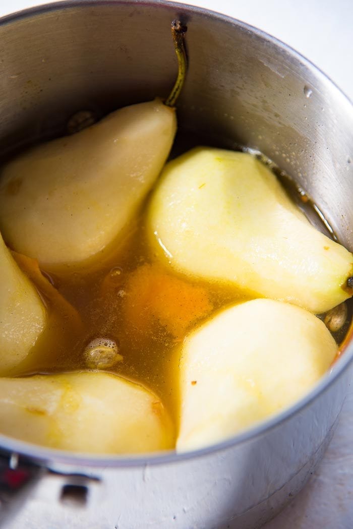 Peeled pears in the saucepan with poaching liquid, before being poached. 