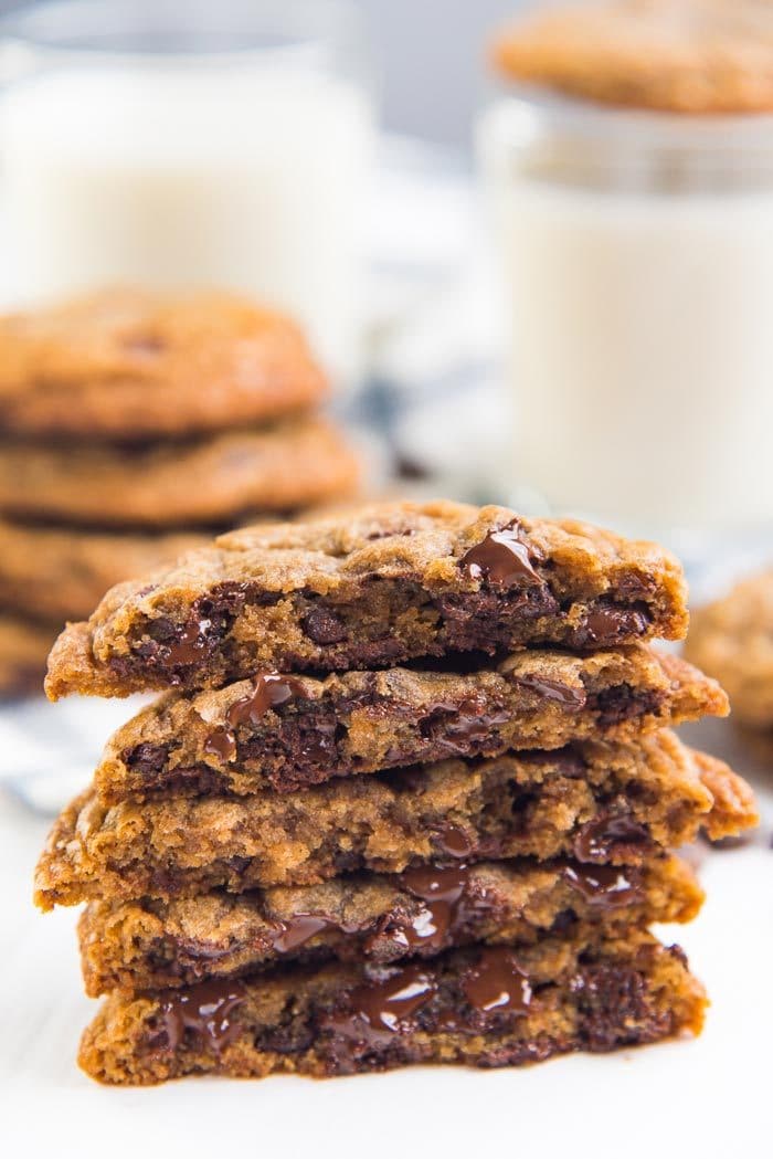 Halved chocolate chip cookies stacked on top of each other to show the melted gooey chocolate inside.