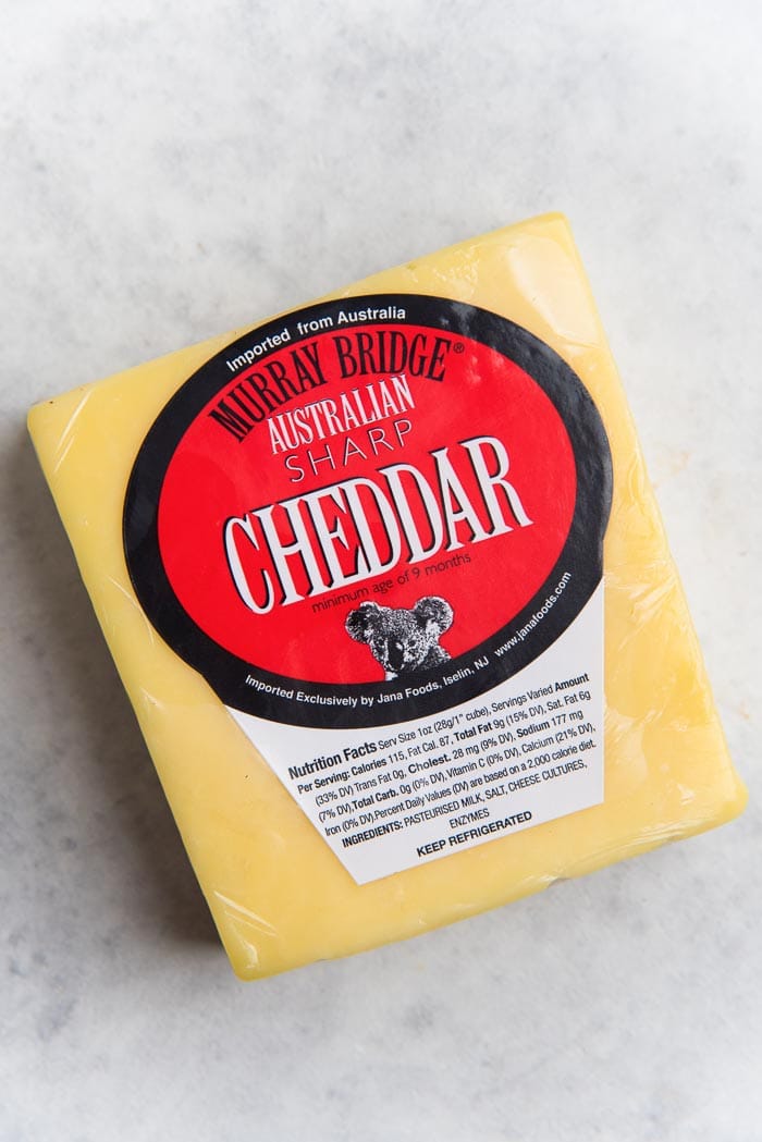 A block of cheddar cheese on a white table top