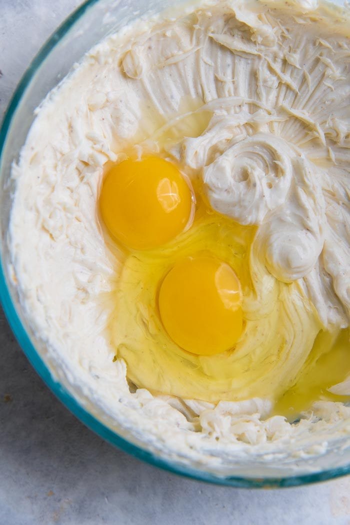 Cheesecake stuffed gingerbread cake recipe process - Eggs being added to the nutmeg flavored cheesecake layer.