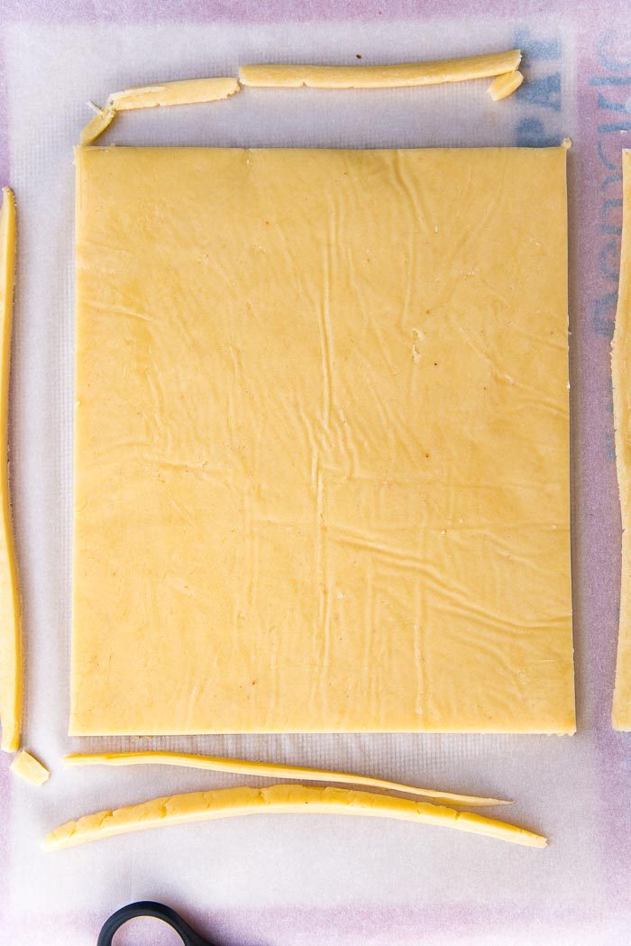 The chilled dough disc on a parchment paper, with the edges trimmed off before being cut into shapes.
