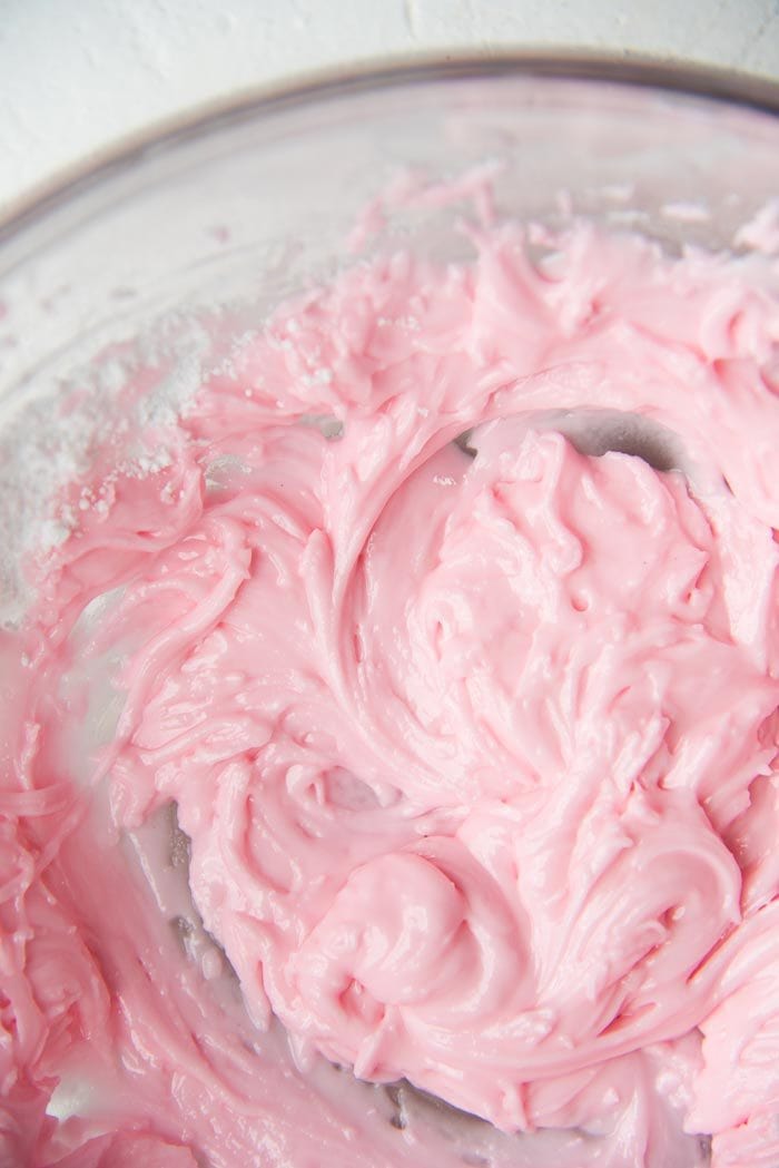 Sugar cookie frosting for hundreds and thousands biscuits or funfetti cookies, mixed to a smooth paste in a glass bowl.