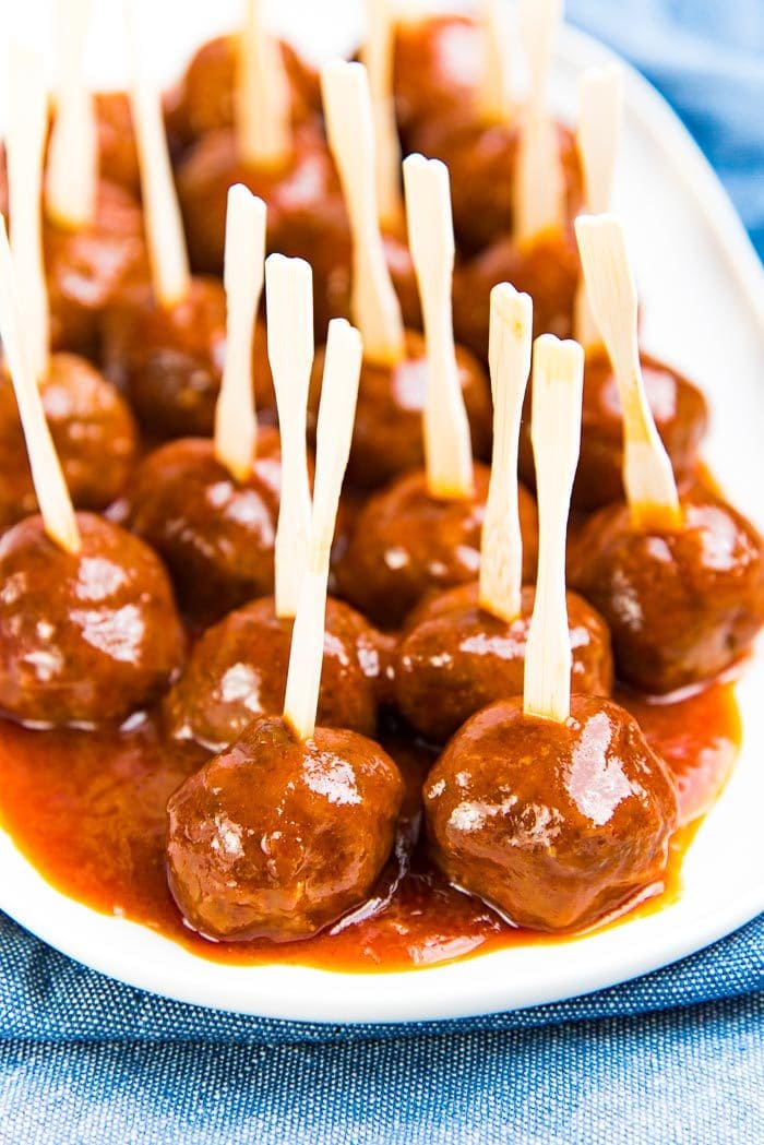 Sweet and spicy cocktail meatballs made without grape jelly, served on a white platter, with cocktail picks in them.