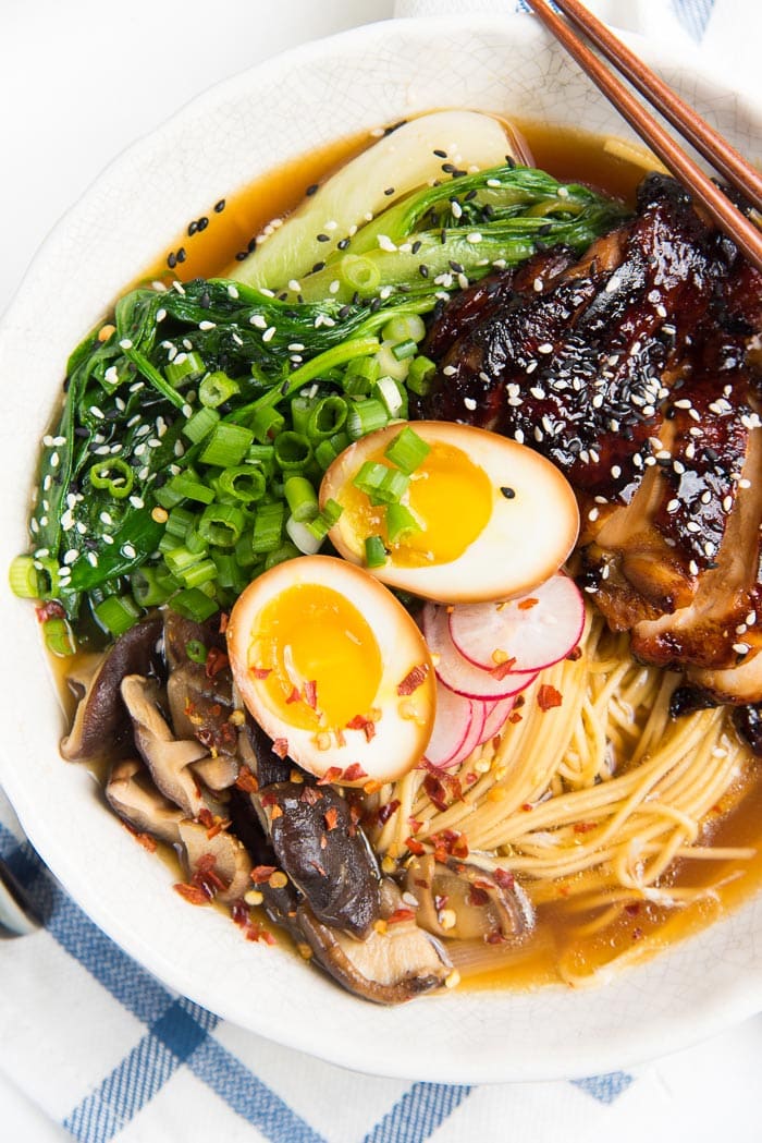 An overhead view of Easy chicken ramen, showing the ramen noodles, ramen egg, grilled chicken, greens, mushrooms and radishes.