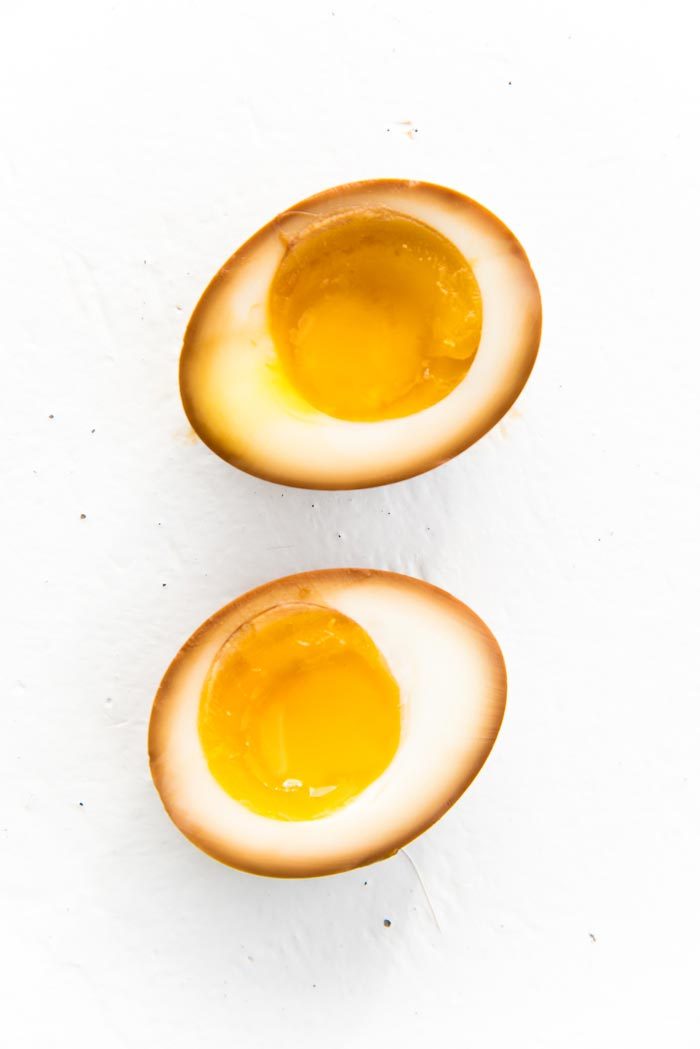 A close up of a ramen egg cut in half to show the marinated edges and the runny yolks.
