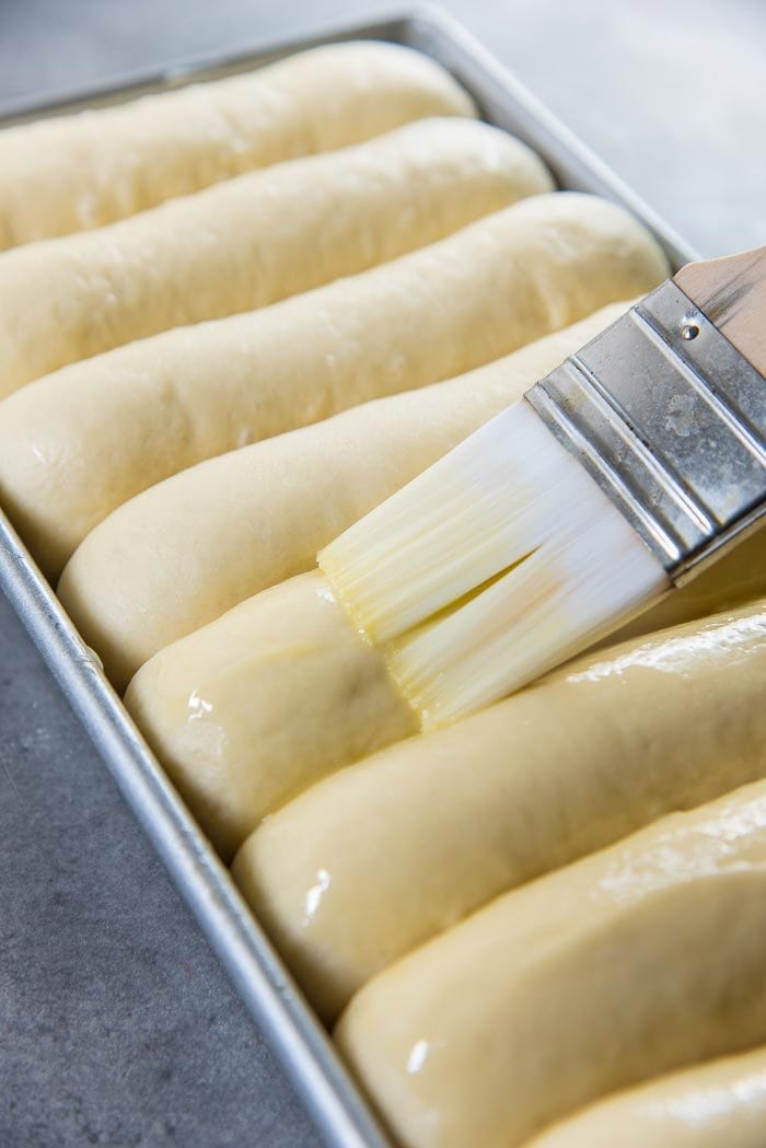 Process of making New England Hot Dog Buns (Lobster roll buns) - Brushing the egg wash over the top of the proofed hot dog buns.