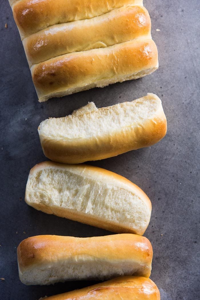 Lobster Rolls buns, untoasted, on a grey surface, showing the soft sides, and the golden brown tops.