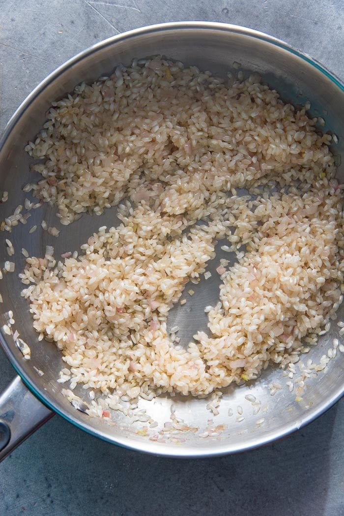 Arborio rice being sauteed in a pan until toasty.