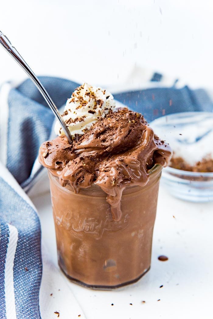 Chocolate ice cream in a jar, with whipped cream on top with shaved chocolate on top.