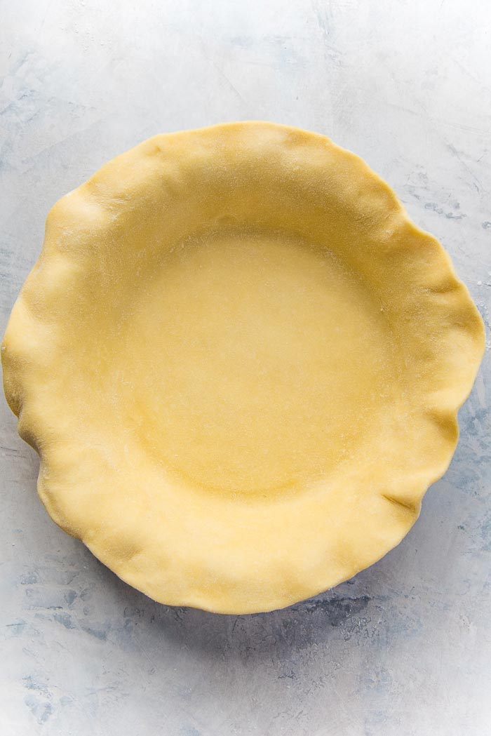 A buttery pie crust, lining the pie plate for the quiche.