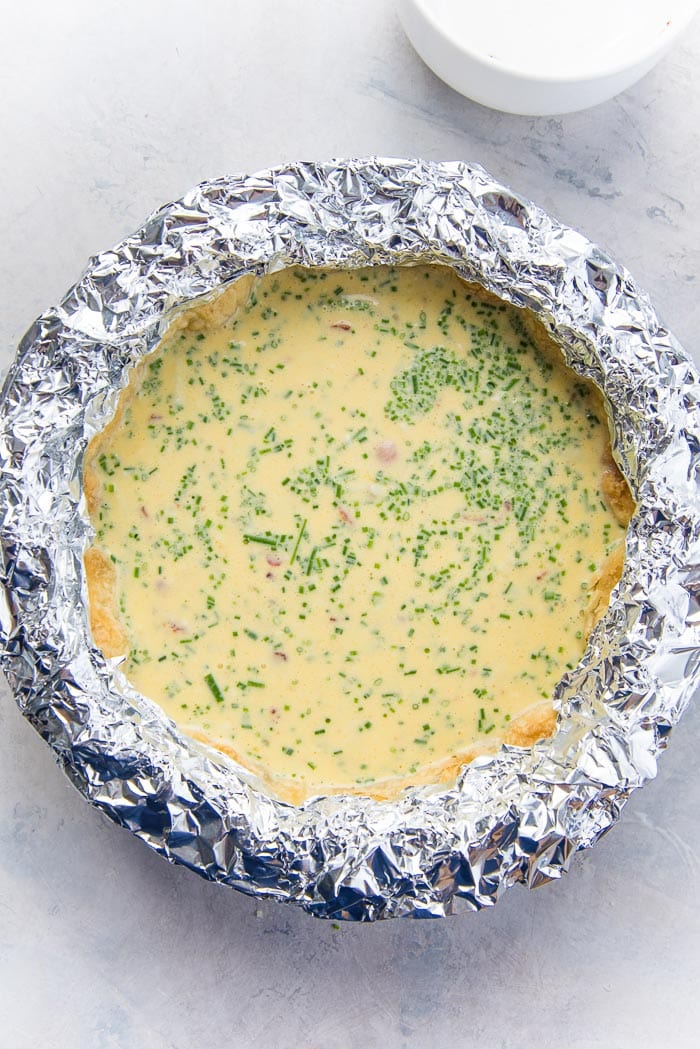 How to make a quiche lorraine - Foil covering the edges of the crust, with the middle filled with the egg filling.