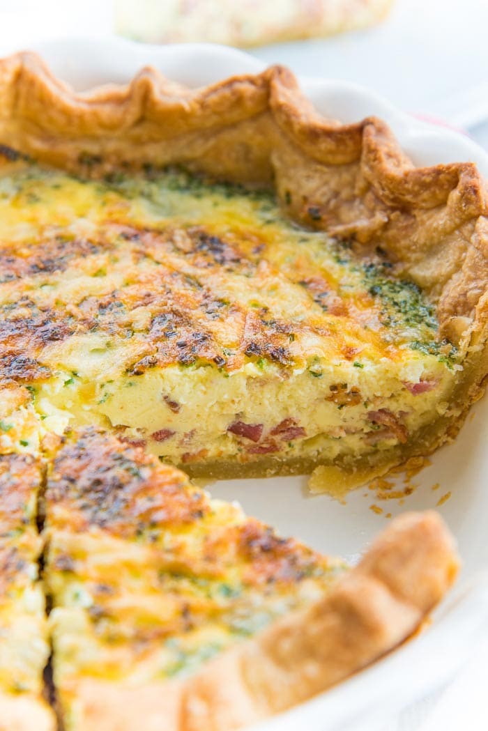 Quiche Lorraine in a quiche dish with one slice taken out