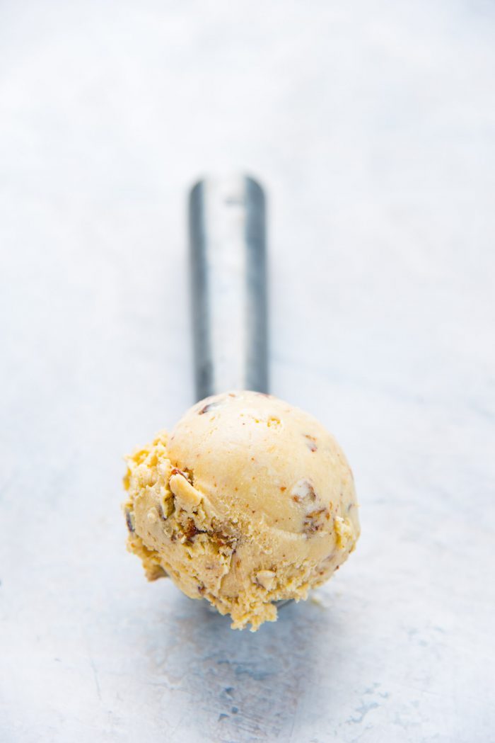 A single scoop of brown butter butterscotch pecan ice cream on a ice cream scoop