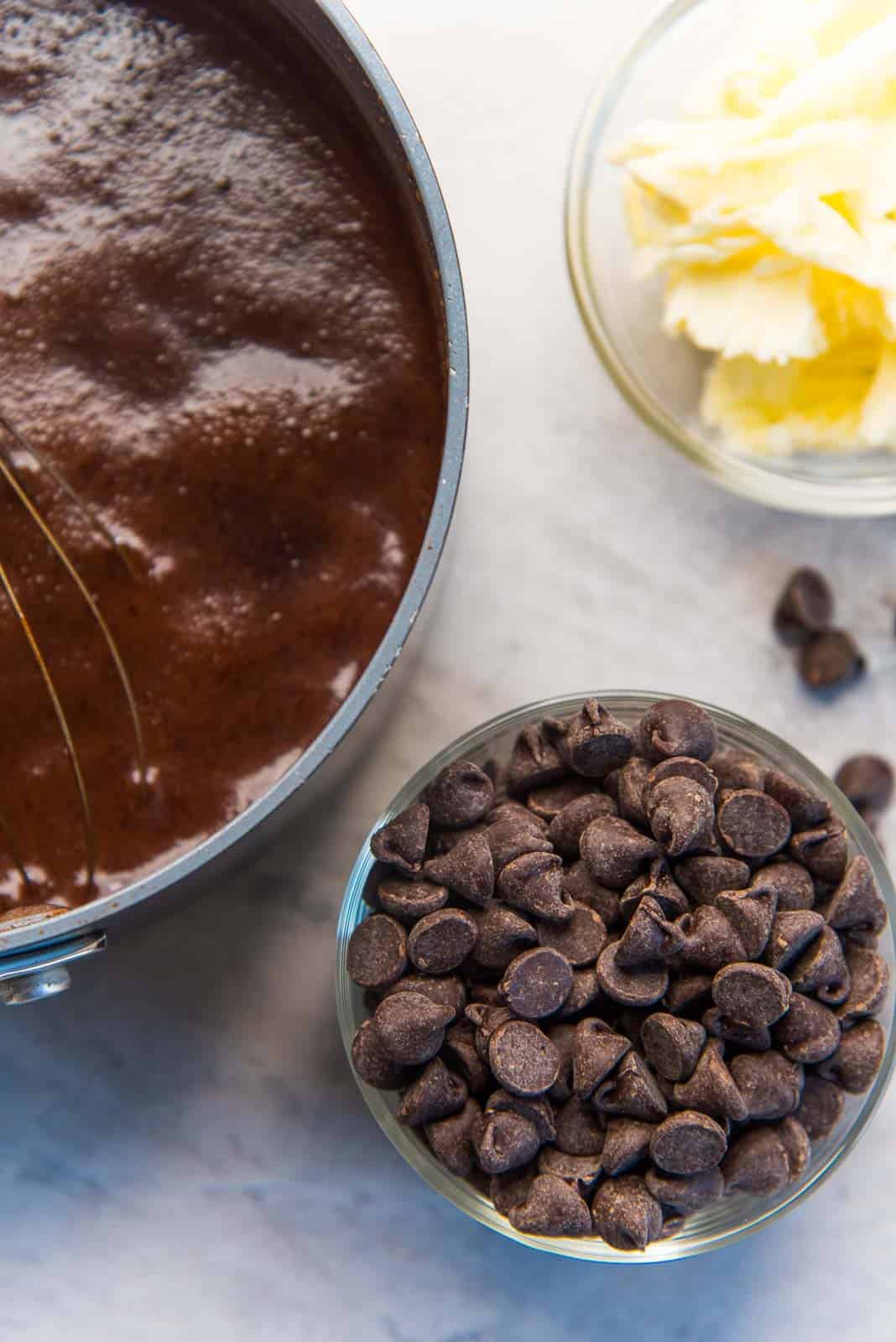Bubbling cocoa mix in a saucepan, with chocolate and butter on the side
