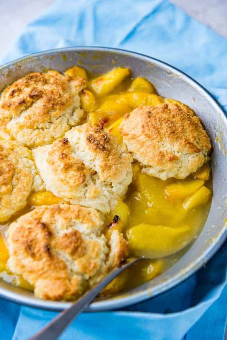 A close up of the baked fresh peach cobbler, with one biscuit topping served