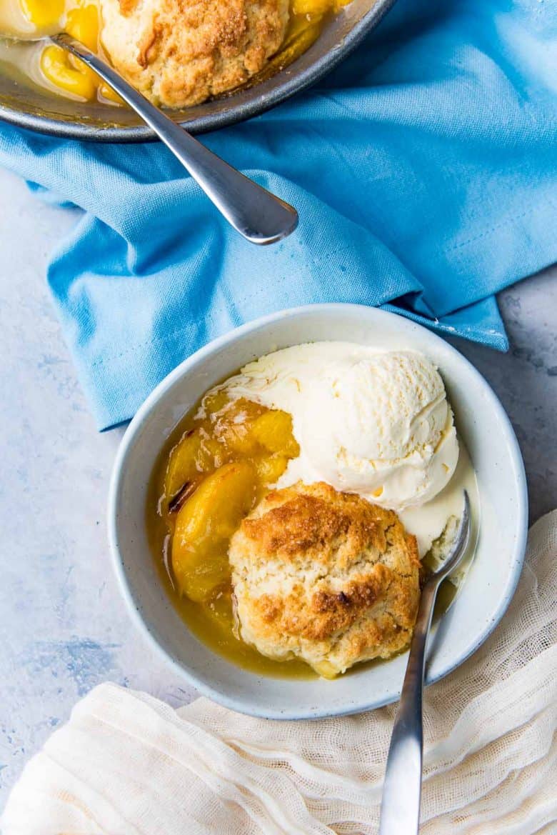 Overhead view of peach cobbler served in a bowl with a scoop of ice cream