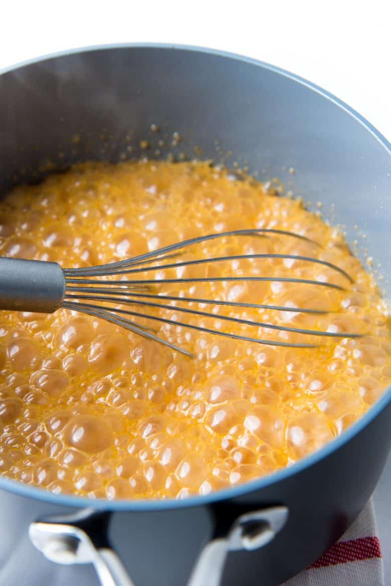 Adding warm heavy cream to caramel sauce and caramel bubbling