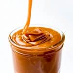 Salted caramel sauce being poured into a glass jar.