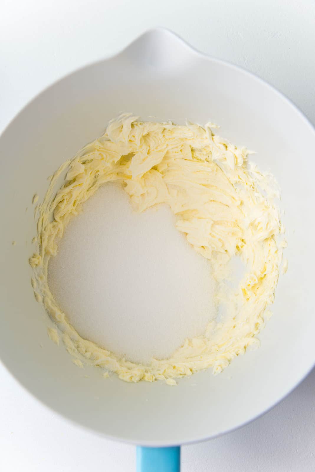 Sugar added to creamed butter in a mixer bowl.