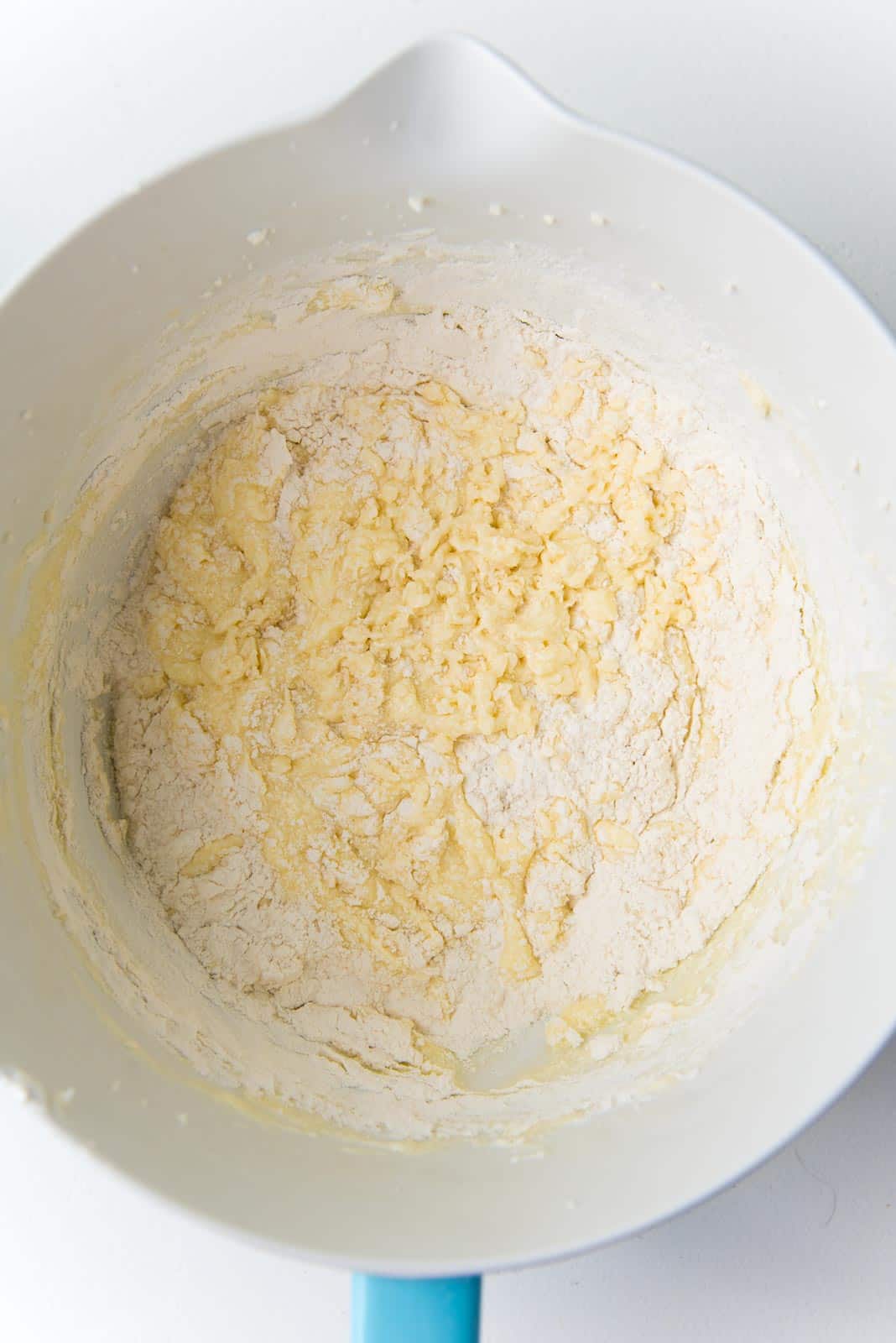 Folding flour into the cupcake batter in a mixer bowl.