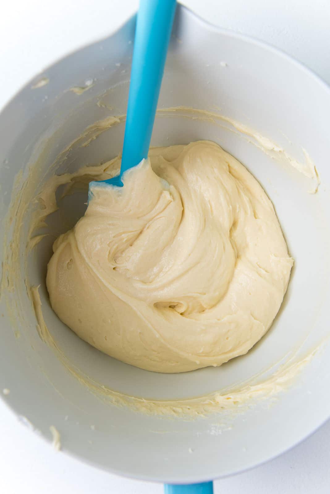 Smooth vanilla cupcake batter in a bowl with a rubber spatula. 