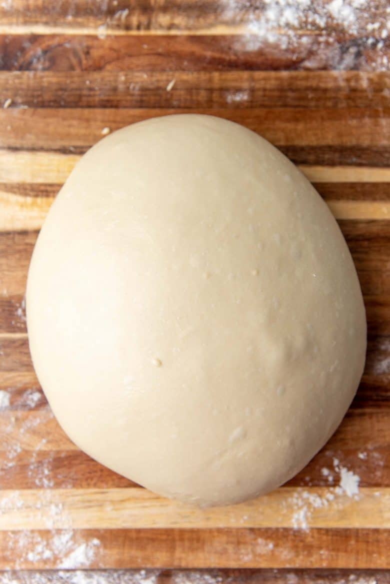 Milk bread dough formed into a smooth dough ball on a work surface.