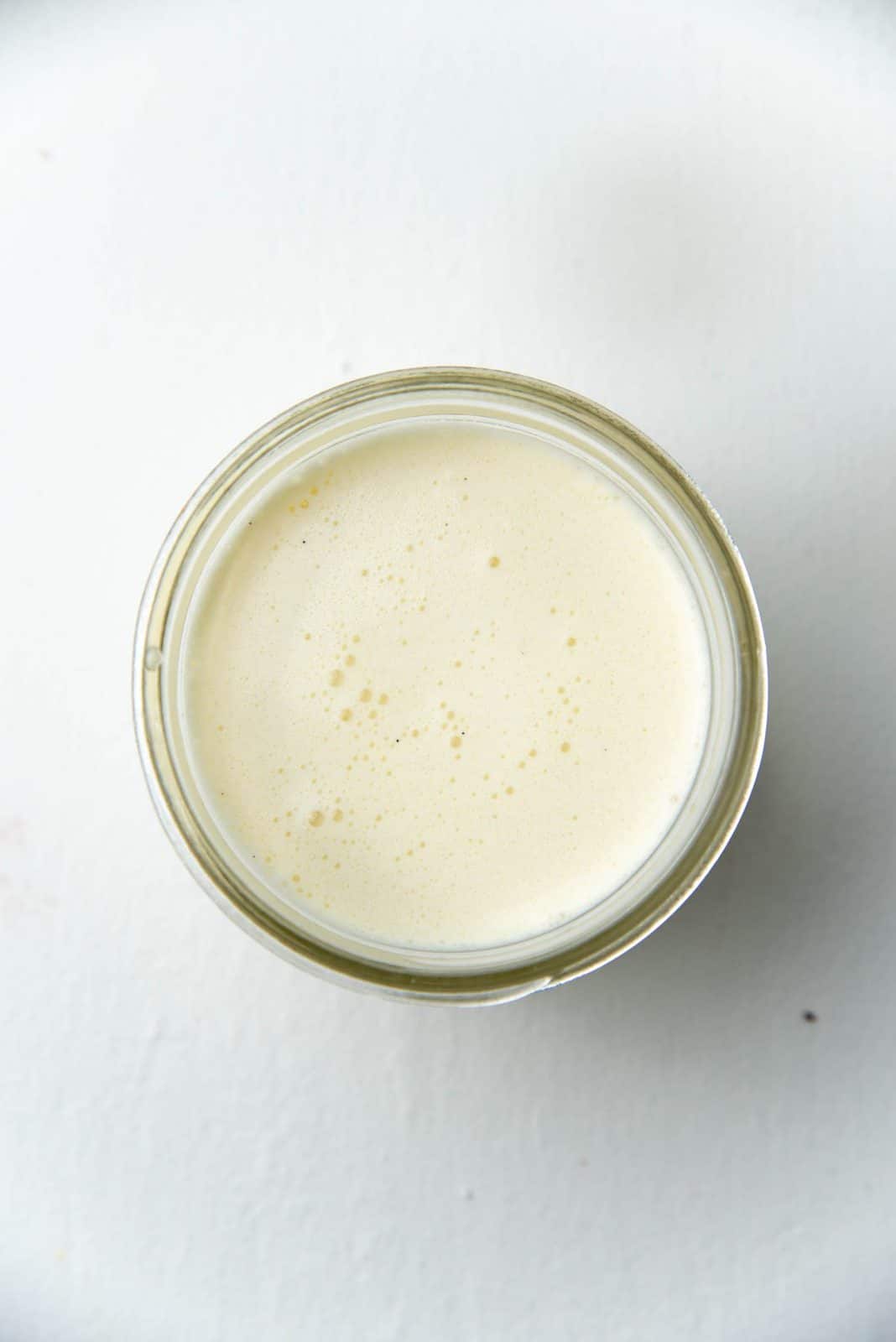 Overhead view of the custard poured into a glass jar with bubbles on the surface.