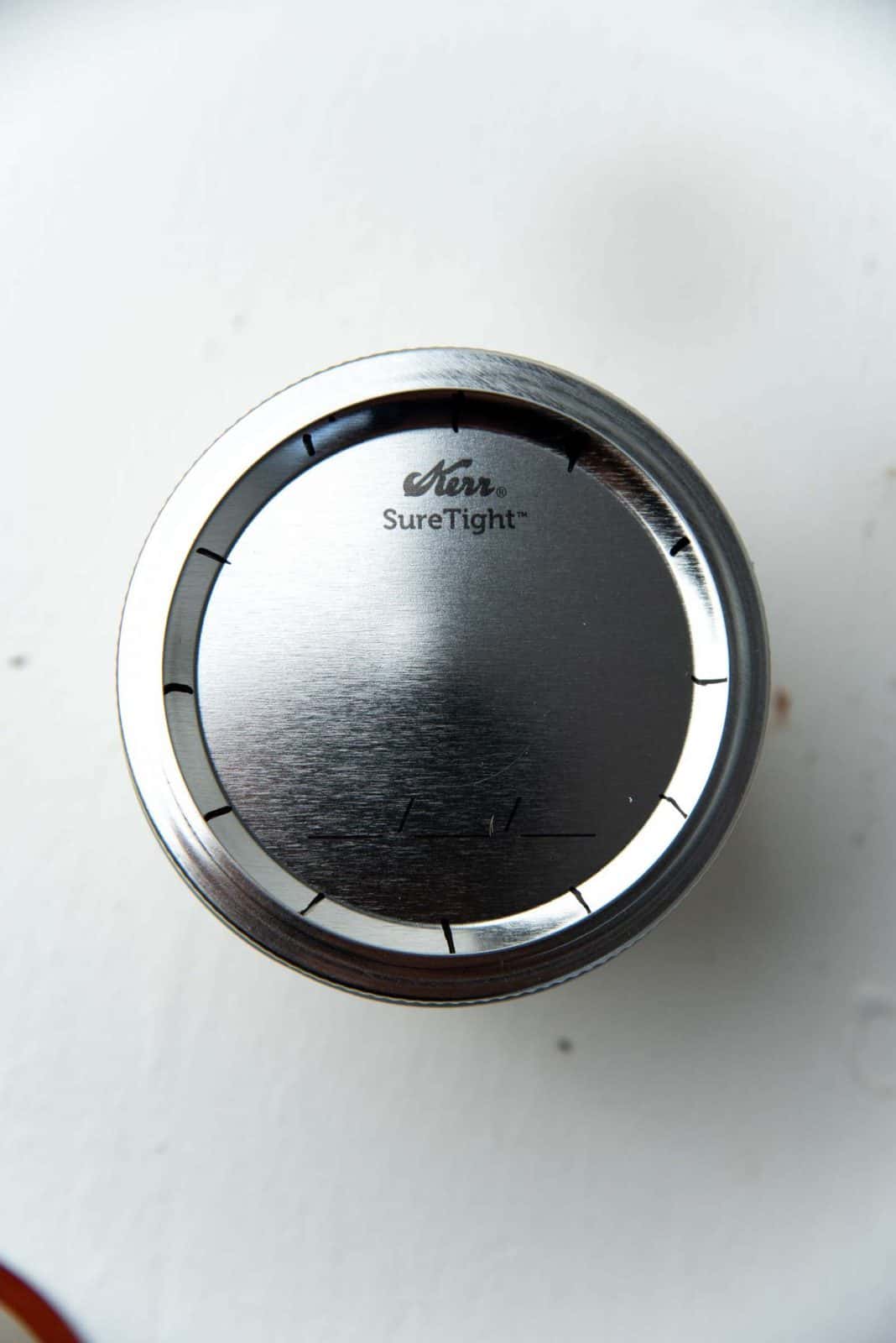 Close up of the mason jar metal lid with 12 markings on it like on a clock face. 