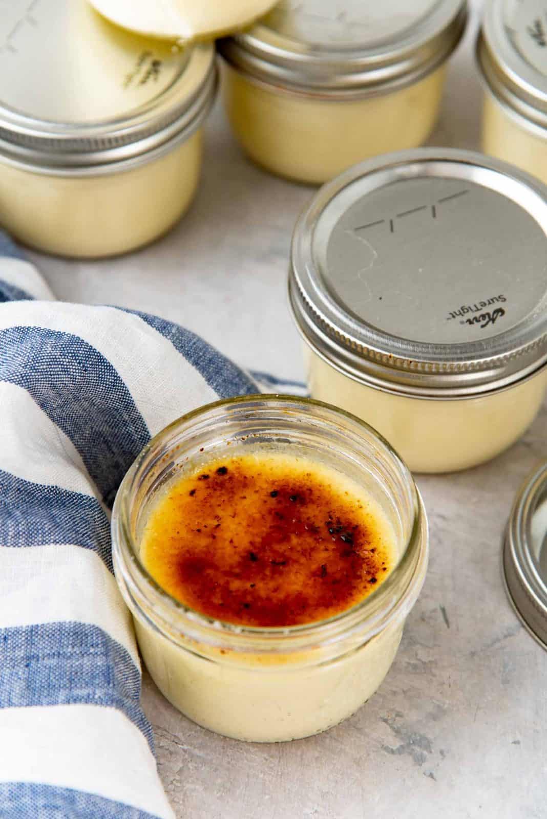 Sous vide caramel brulee on a gray surface with a blue and white striped cloth next to it.
