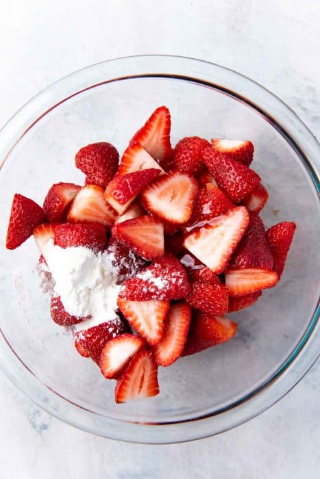 Strawberries in a large bowl with cornstarch, sweetener and other flavorings