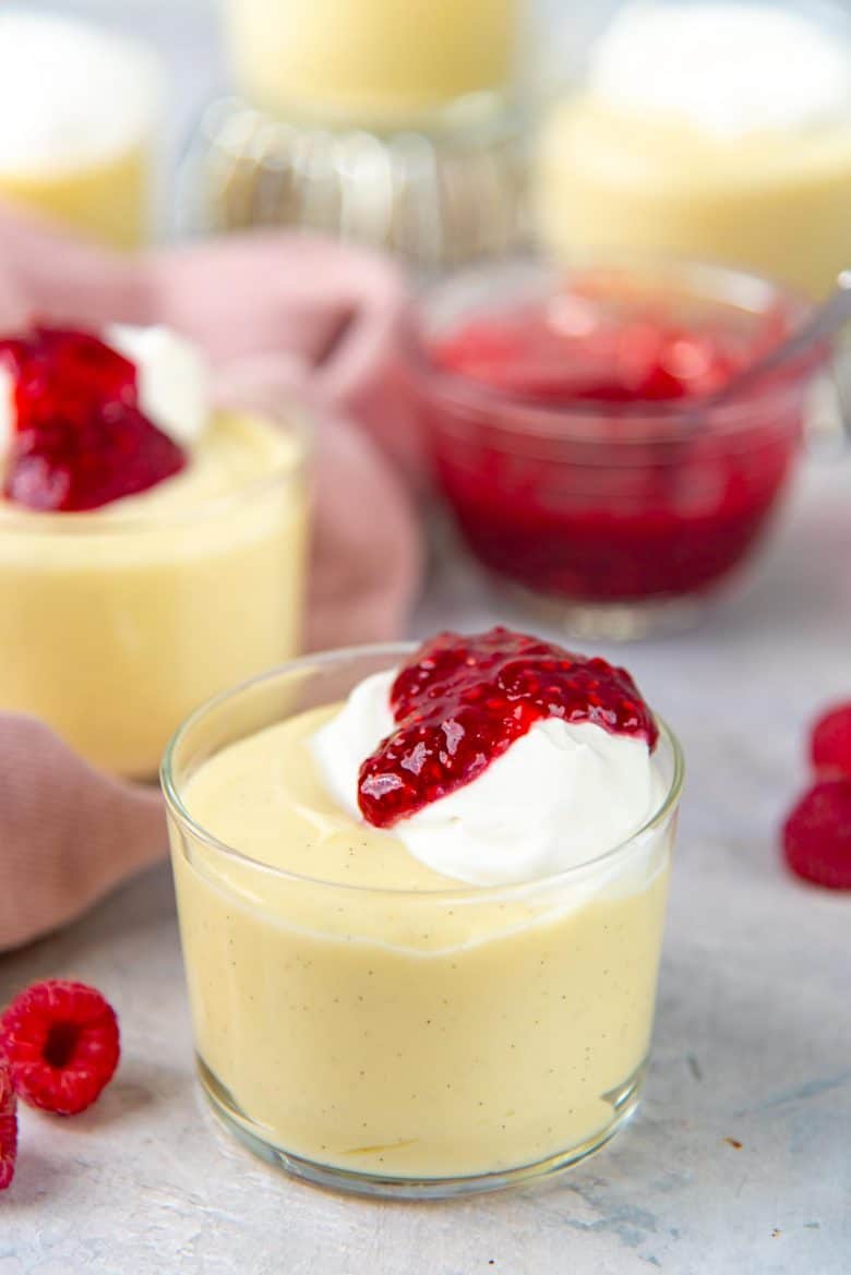 Homemade vanilla pudding topped with whipped cream and raspberry coulis
