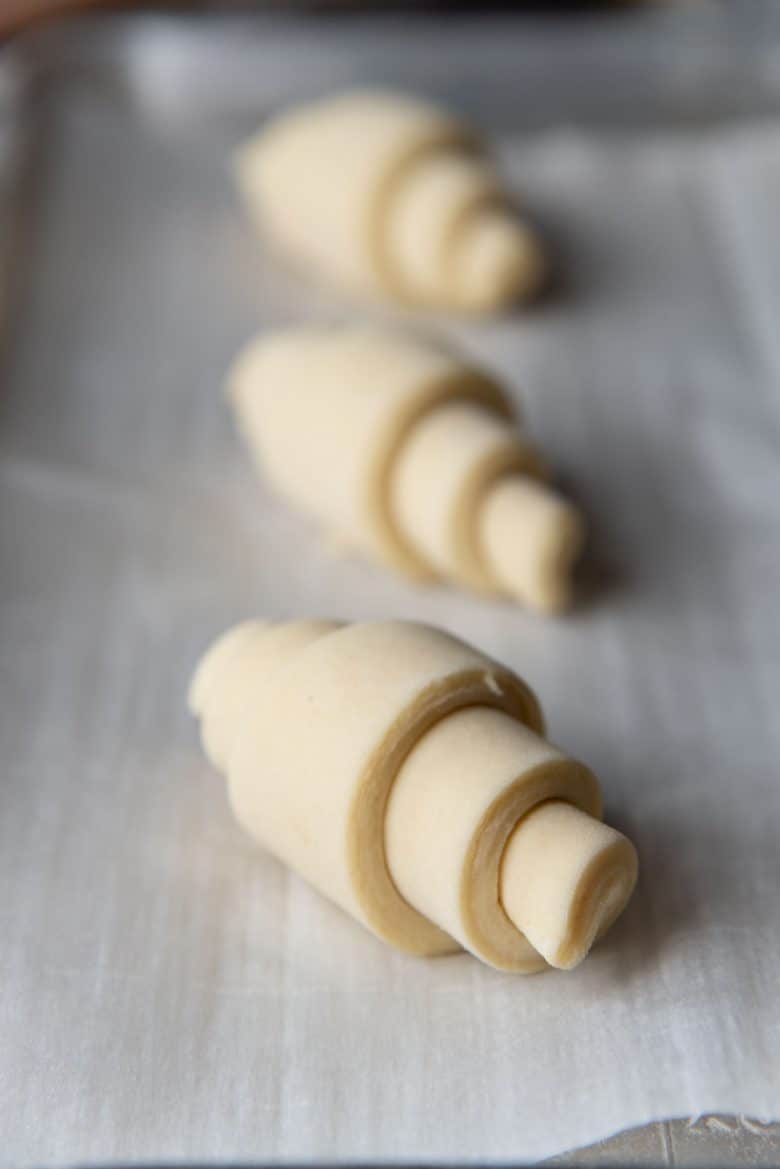 Rolled up unproofed croissants on a baking tray
