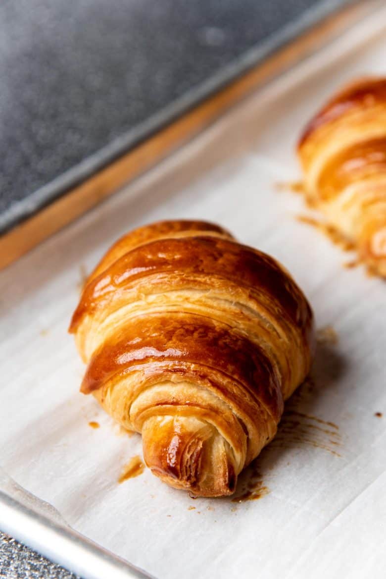 A flaky croissant on a baking sheet