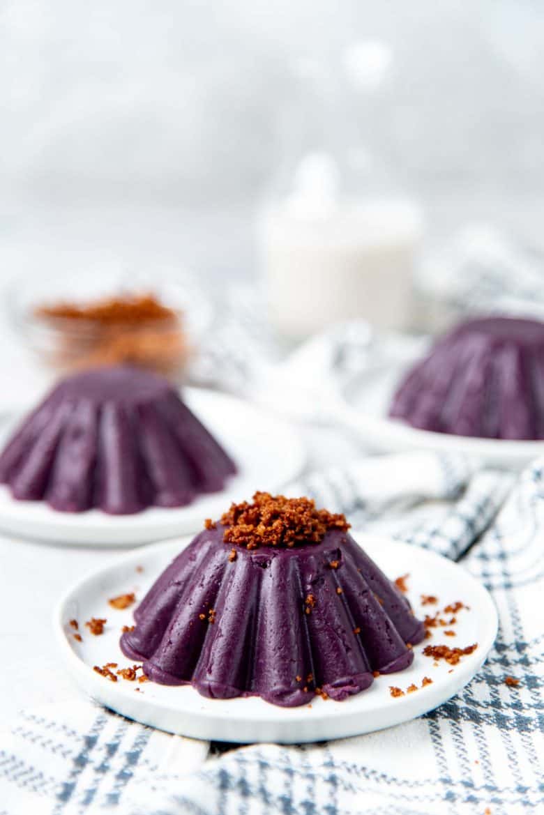 Ube halaya molded and placed on a white plate with latik on top