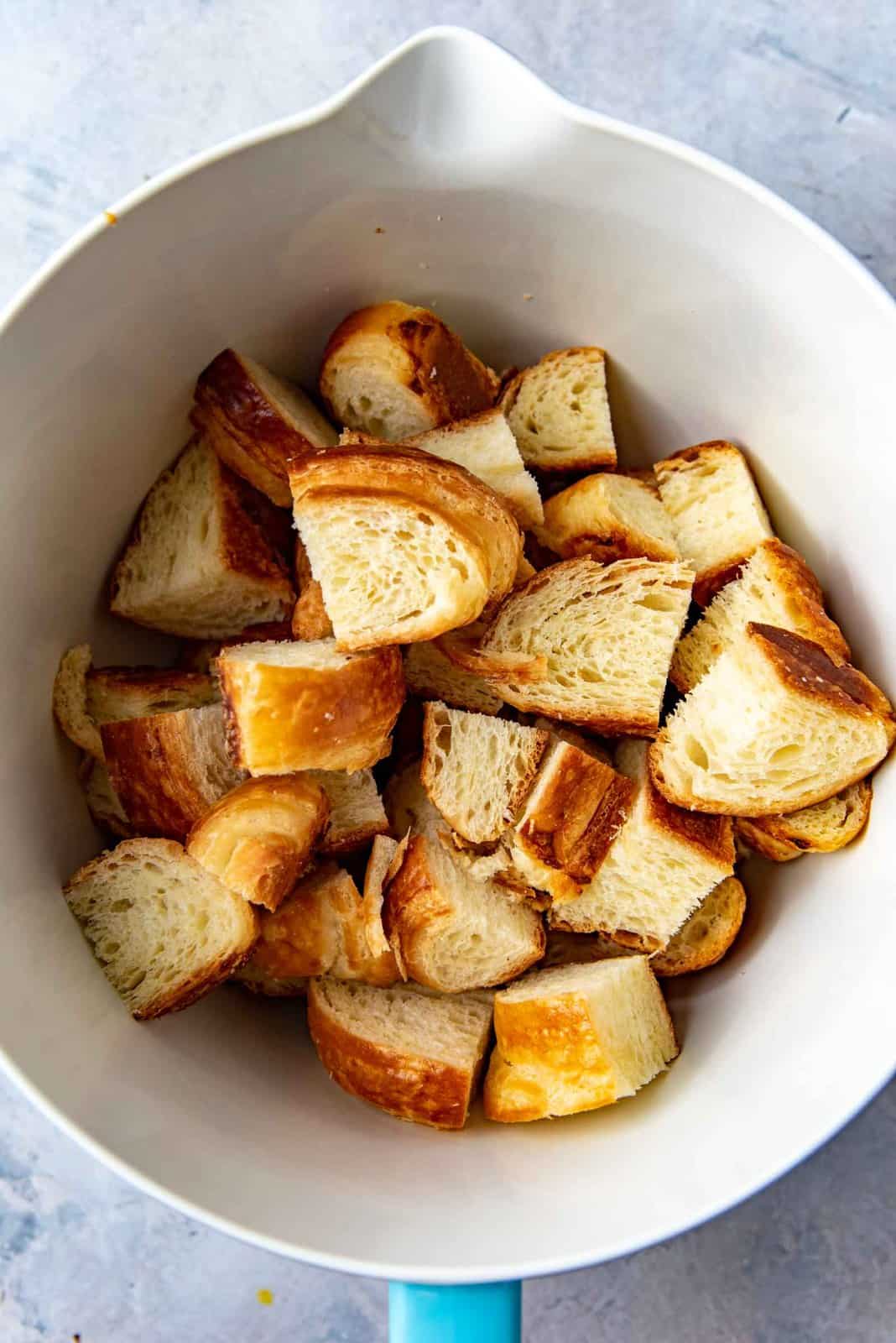 The cut up day old french croissants in a bowl