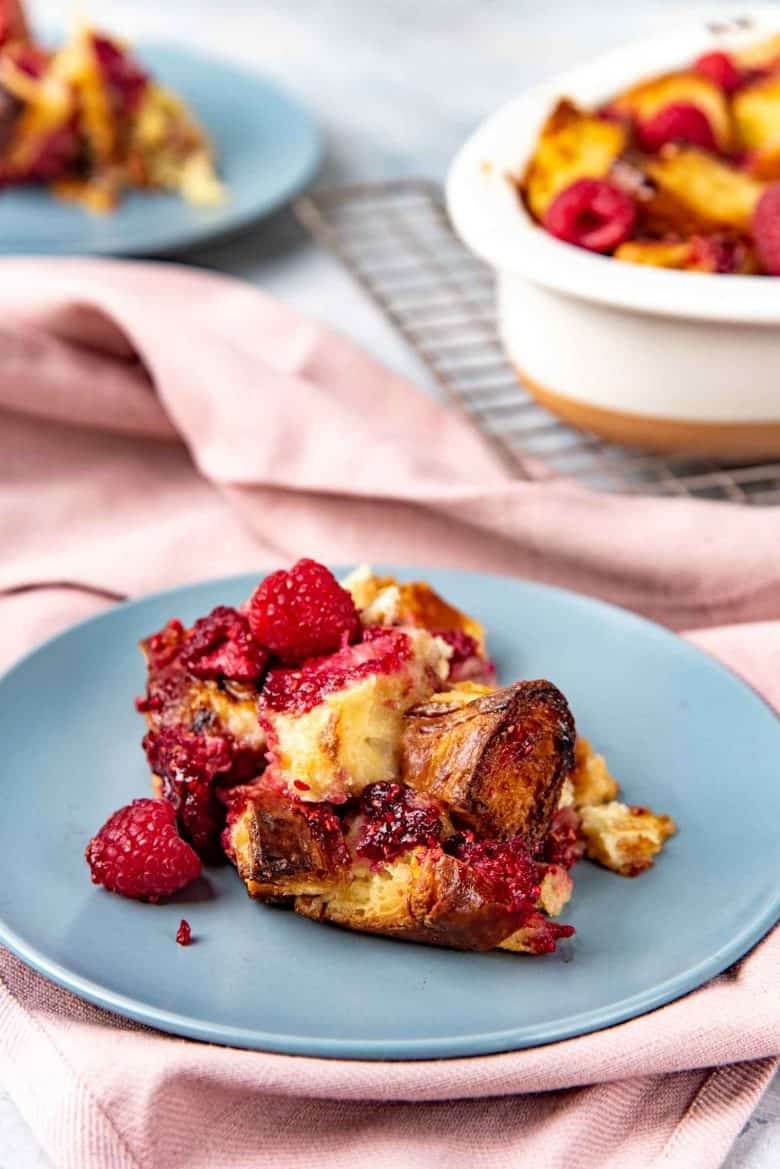 Croissant bread pudding with raspberries served on a plate.