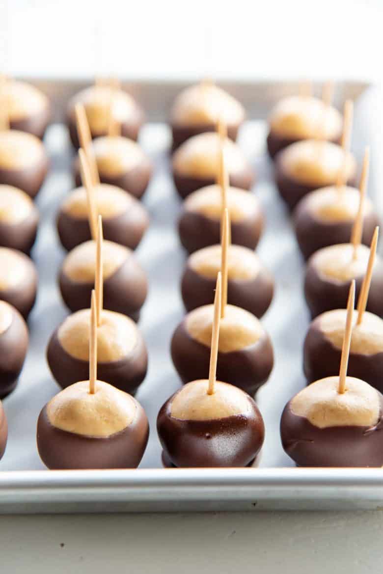 Peanut butter buckeyes dipped partially in chocolate and placed on parchment paper to set