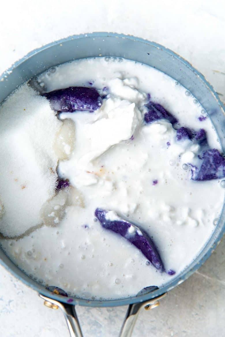 Adding coconut milk to the ube mix in a pot