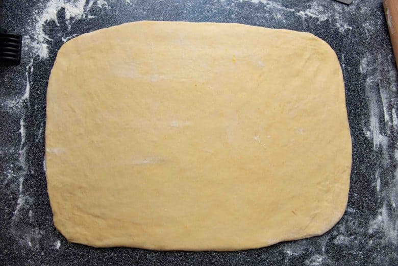 Brioche dough rolled out into a rectangle using a rolling pin