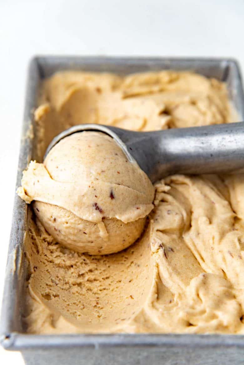 A close up of a scoop of date and tahini ice cream scooped from the ice cream container