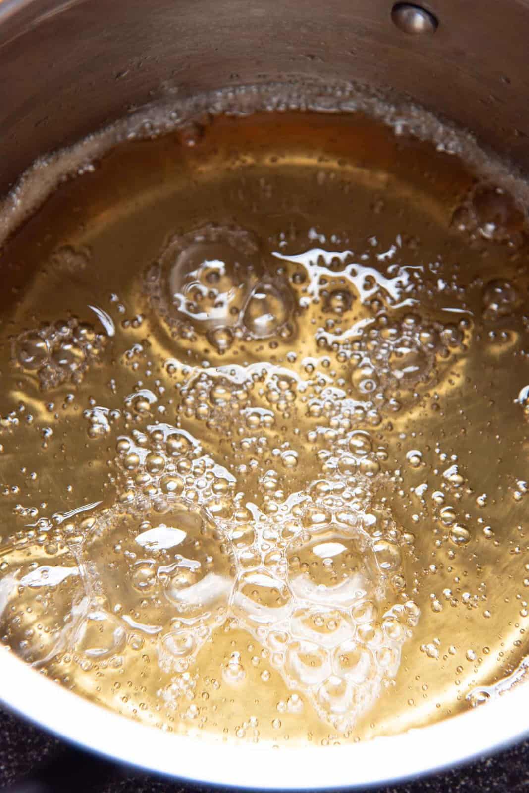 The sugar syrup boiling in the saucepan