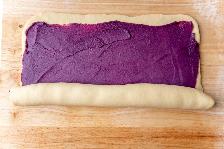 Rolling up the bread dough spread with the ube jam