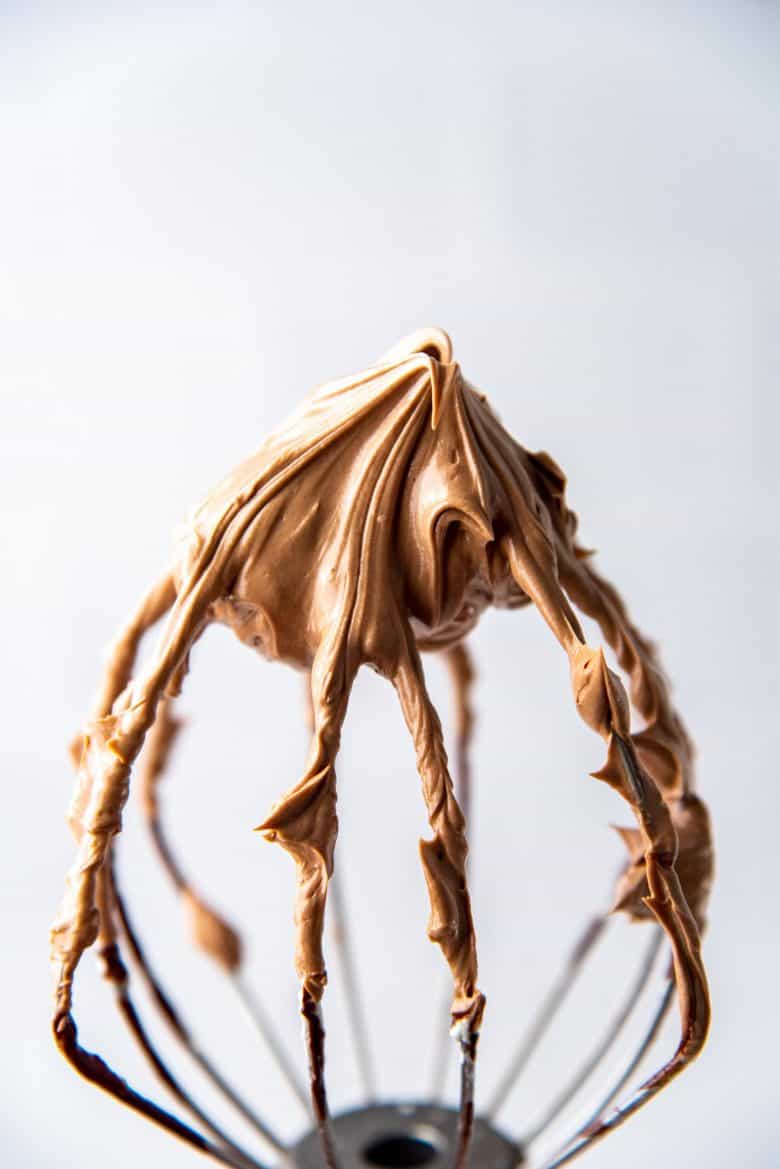 A whisk attachement with chocolate swiss meringue buttercream on it