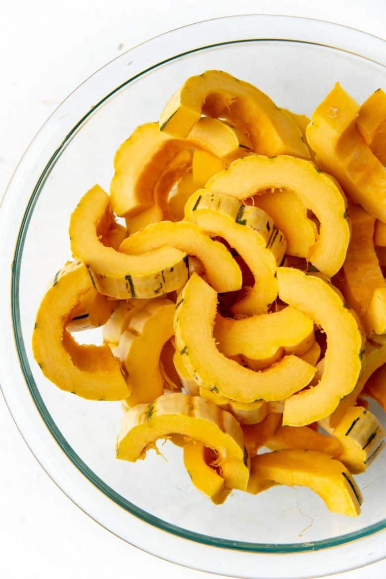 Sliced delicata squash in a large glass bowl