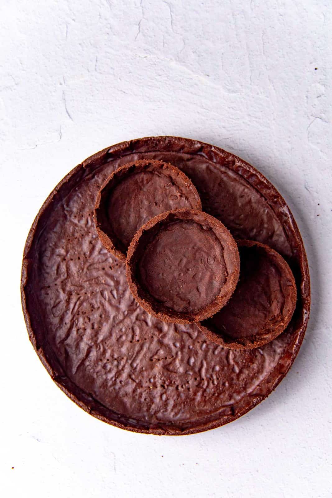 A chocolate tart shell brushed cocoa butter and three mini tarts