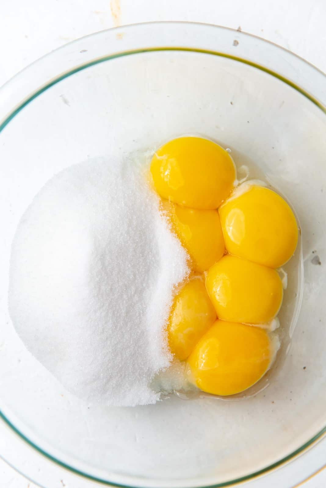 Egg yolks and sugar in a large glass bowl.