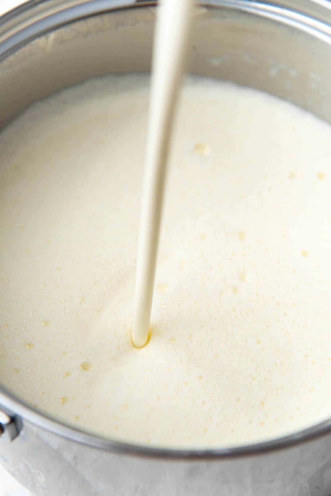 Pouring cream to the eggnog base in the saucepan.