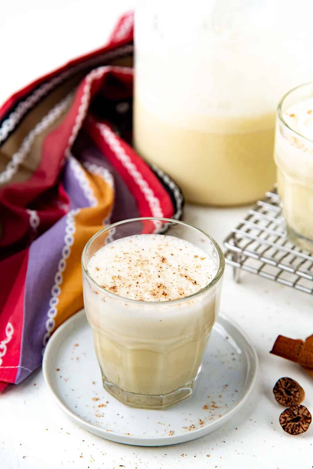 Homemade eggnog served in a glass with nutmeg sprinkled on top.